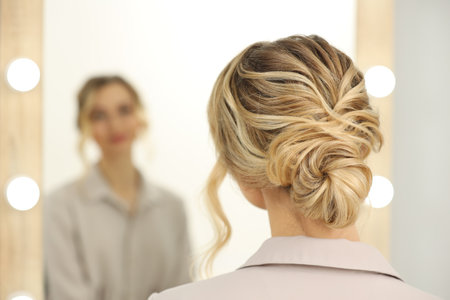 Woman with beautiful hair style looking at mirror indoors. Space for text