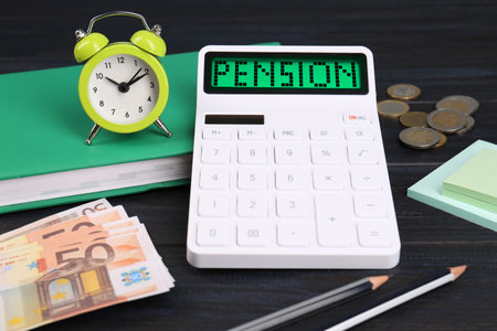 Calculator with word Pension, money, alarm clock and stationery on dark wooden table, closeupの写真素材