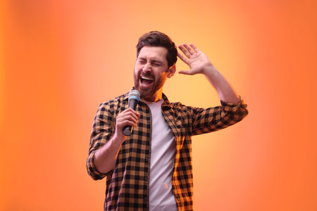 Handsome man with microphone singing in color lightsの写真素材