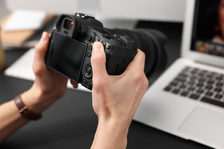 Professional photographer with digital camera at table indoors, closeupの写真素材