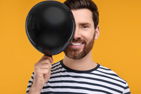 Happy man with black balloon on yellow backgroundの写真素材