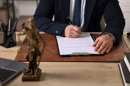 Notary writing notes at wooden table in office, closeup