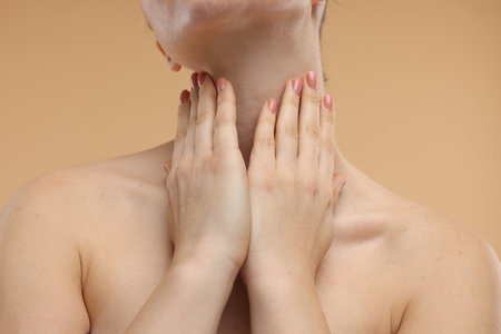 Woman touching her neck on beige background, closeupの写真素材