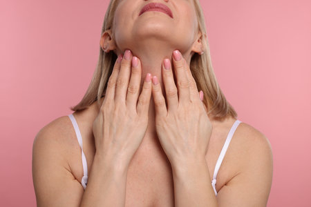 Woman touching her neck on pink background, closeupの写真素材