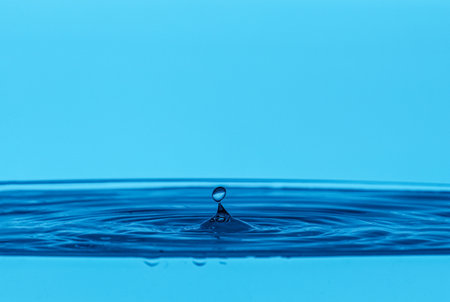 Splash of clear water with drop on blue background, closeupの写真素材