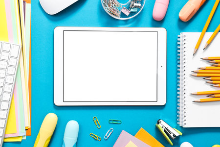 Modern tablet and stationery on light blue background, flat lay. Space for textの写真素材