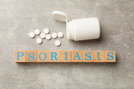 Word Psoriasis made of wooden cubes with letters and pills on light gray textured table, flat layの写真素材