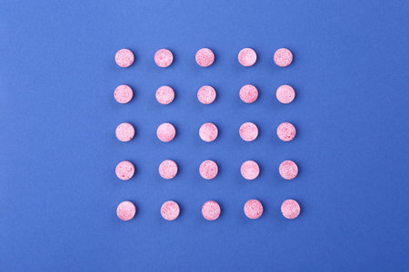 Many pink vitamin pills on blue background, flat layの写真素材
