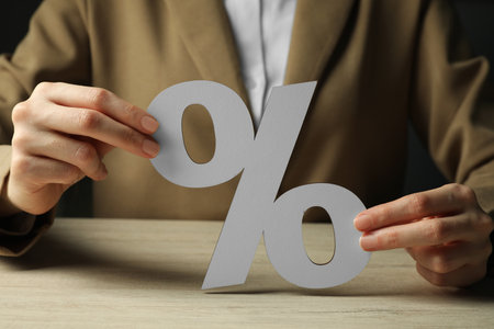Woman holding percent sign at wooden table, closeupの写真素材