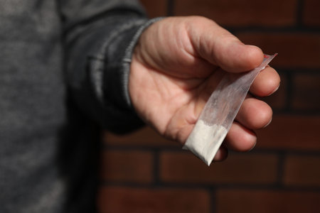 Drug addiction. Man with plastic bag of cocaine on blurred background, closeupの写真素材