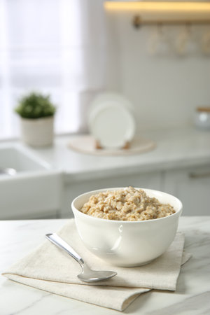 Breakfast time. Tasty oatmeal in bowl on white marble table. Space for textの写真素材