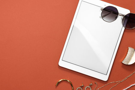 Modern tablet, sunglasses and bijouterie on color background, flat lay. Space for text
