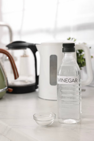 Cleaning electric kettle. Bottle of vinegar and baking soda on countertop in kitchenの写真素材