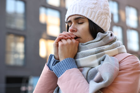 Sick young woman coughing outdoors. Cold symptomの写真素材