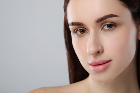 Beautiful young woman with healthy skin on light gray background, closeup. Space for textの写真素材