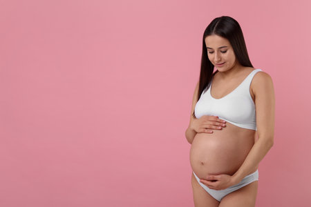 Beautiful pregnant woman in stylish comfortable underwear on pink background, space for textの写真素材