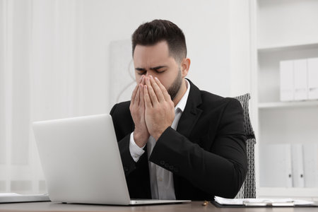 Sick man coughing at workplace in officeの写真素材