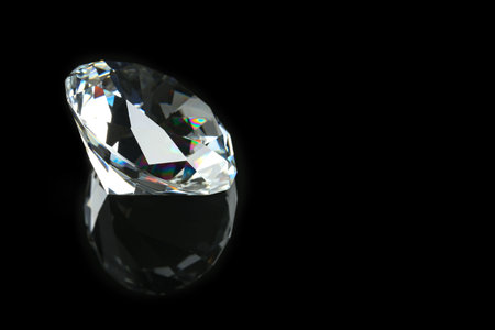 Beautiful shiny diamond on black mirror surface, closeup. Space for textの写真素材