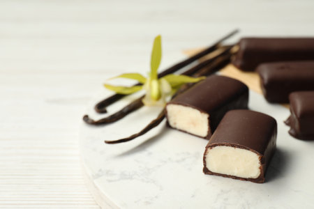Glazed curd cheese bars, vanilla pods and flower on white table, closeupの写真素材