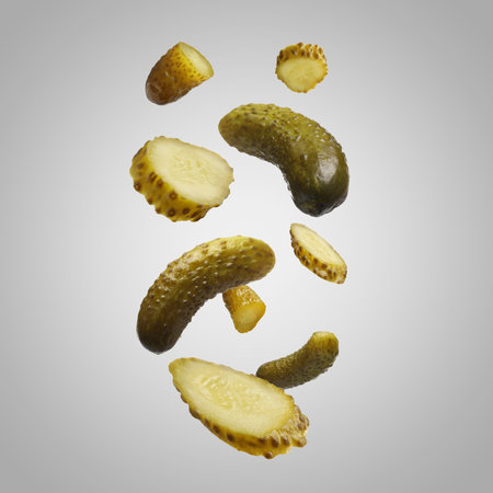 Tasty pickled cucumbers falling on light gray backgroundの写真素材