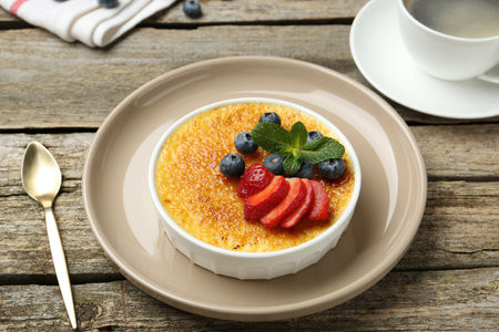 Delicious creme brulee with berries and mint in bowl on wooden table, closeupの写真素材