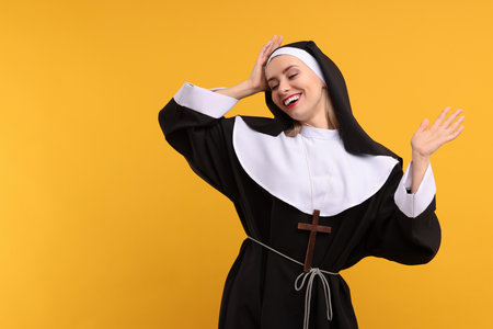 Happy woman in nun habit against orange background. Space for textの写真素材