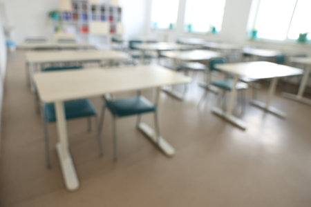 Blurred view of empty school classroom with desks, windows and chairsの写真素材