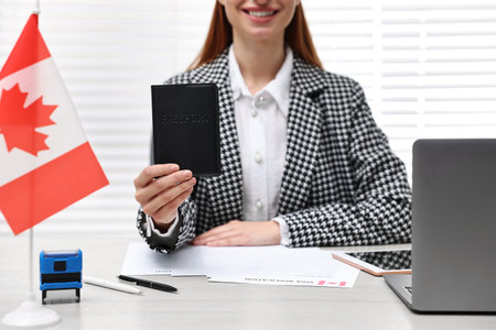 Immigration to Canada. Smiling embassy worker with passport and documents at table in office, closeupの写真素材