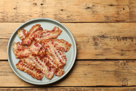 Delicious fried bacon slices on wooden table, top view. Space for textの写真素材