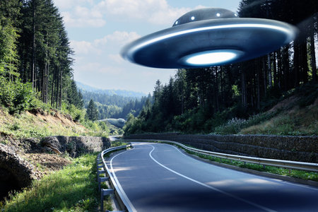 Alien spaceship flying over road in mountains. UFOの写真素材