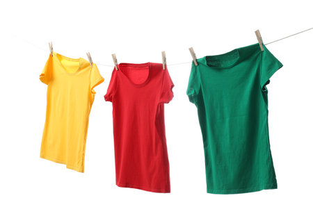 Different bright t-shirts drying on washing line against white backgroundの写真素材
