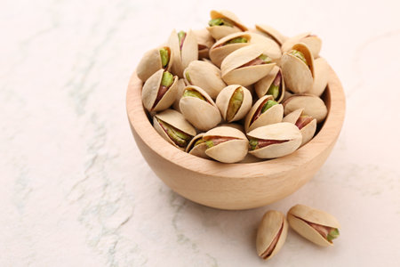 Delicious pistachios in bowl on white textured tableの写真素材