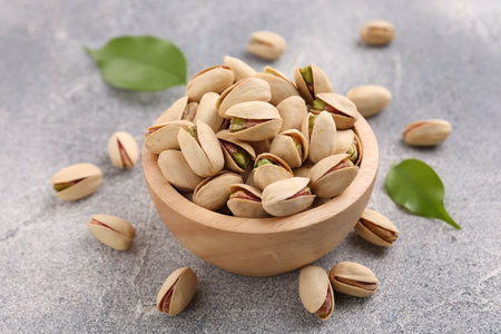 Delicious pistachios in bowl on gray textured tableの写真素材