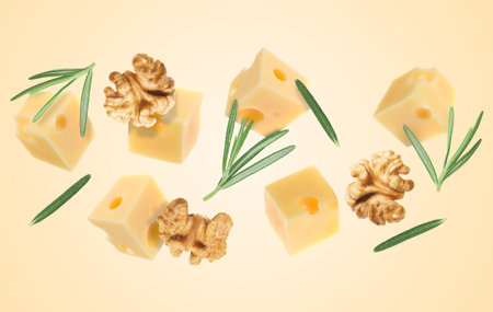 Cheese, walnuts and rosemary flying on beige backgroundの写真素材