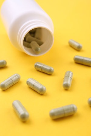 Jar with vitamin capsules on yellow background, closeupの写真素材
