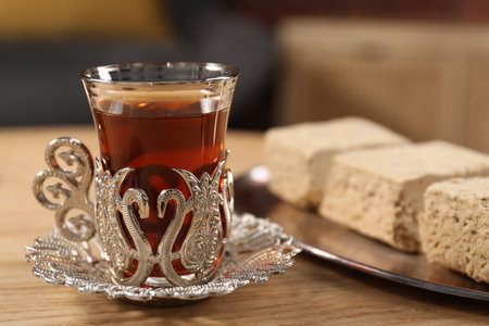 Glass of traditional Turkish tea in vintage holder and tasty halva on wooden table, closeupの写真素材
