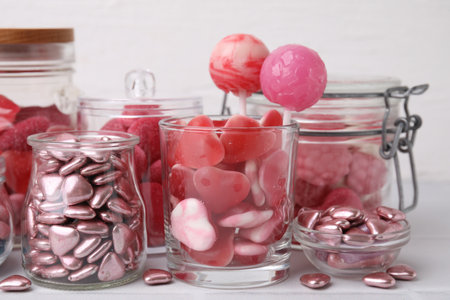 Tasty pink candies in glass jars on white background, closeupの写真素材