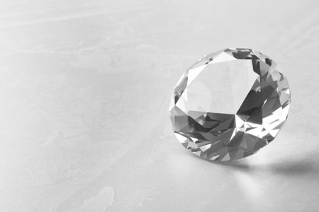 Beautiful shiny diamond on gray table, closeup. Space for textの写真素材