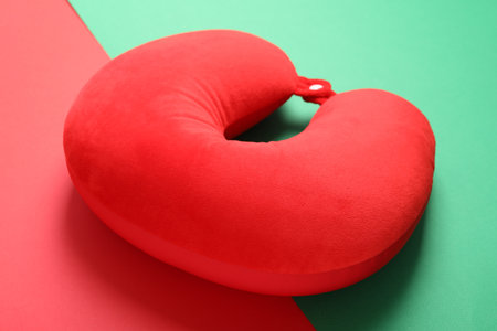 Soft red travel pillow on color background