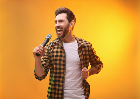 Handsome man with microphone singing on golden backgroundの写真素材