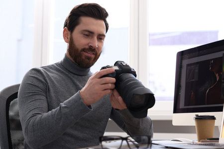 Professional photographer with digital camera at table indoorsの写真素材