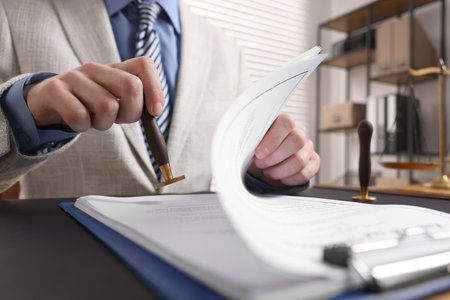 Notary stamping document at table in office, low angle view