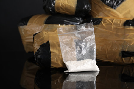 Smuggling and drug trafficking. Packages with drugs on black mirror surface, closeup
