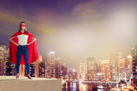 Superhero, motivation and power. Woman in cape and mask on high building in cityの写真素材