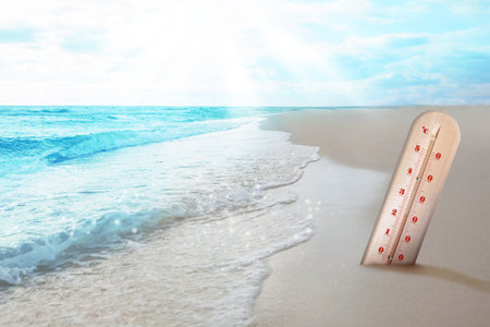 Thermometer in sand on beach during sunny summer dayの写真素材