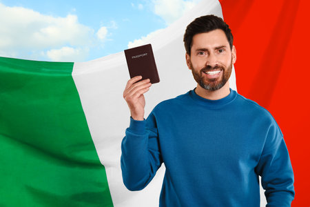 Immigration. Happy man with passport and national flag of Italy against blue sky, space for textの写真素材