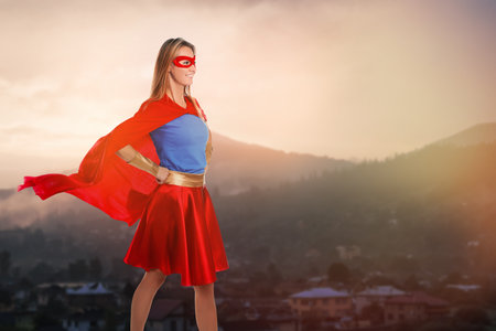 Superhero, motivation and power. Woman in cape and mask on high top in mountainsの写真素材