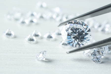 Tweezers with beautiful shiny diamond above light wooden table, closeupの写真素材