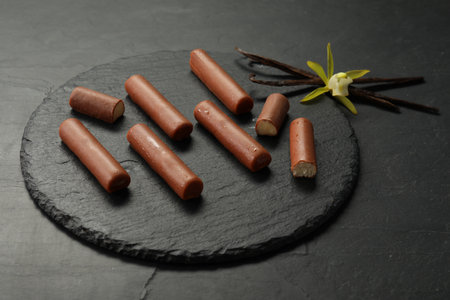 Glazed curd cheese bars, vanilla pods and flower on black tableの写真素材