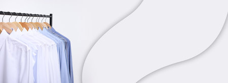 Dry-cleaning service. Different clothes hanging on rack against white background, space for text. Banner designの写真素材